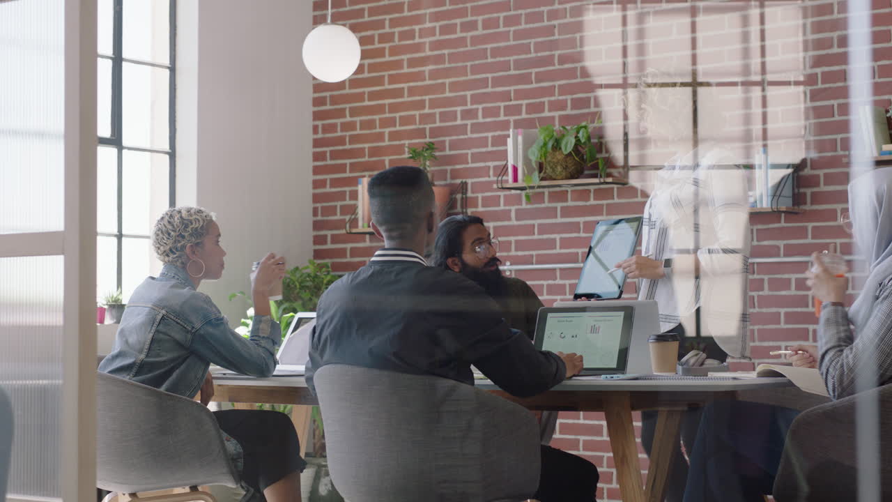 joven mujer de negocios de raza mixta usando una tableta digital presentando datos de gráficos financieros mostrando colegas en la oficina presentación equipo diverso colaborando estrategia de lluvia de ideas