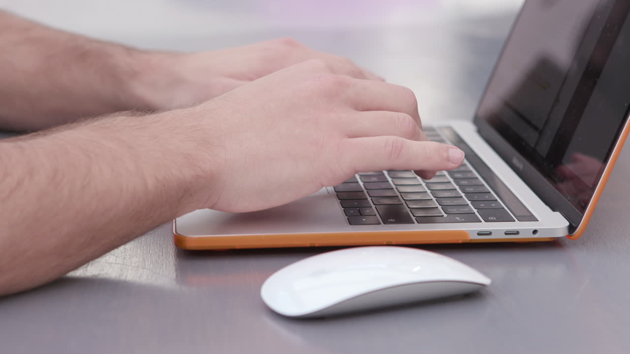 Close of hands on mouse and keyboard of a laptop