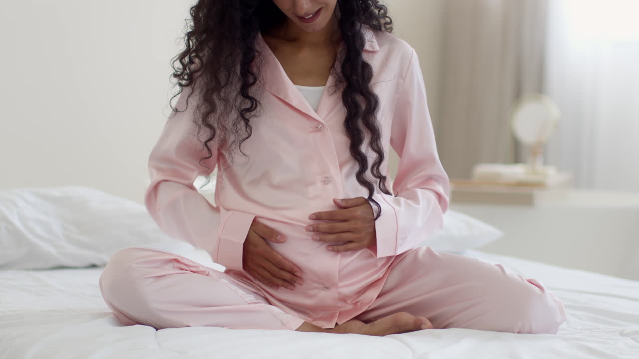 Pregnant woman touching her belly in pajamas