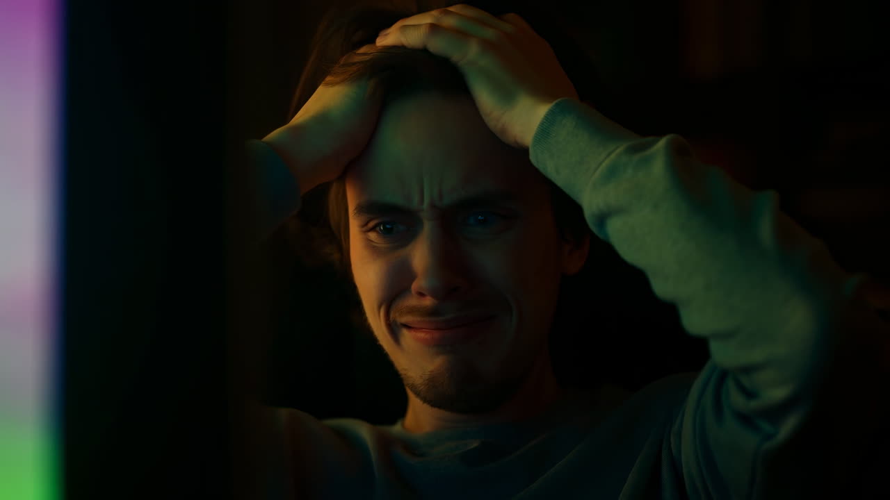 Man Clutching Head In Front Of Screen, Tense Expression, Multicolor Monitor Glow Casting Shadows, Latenight