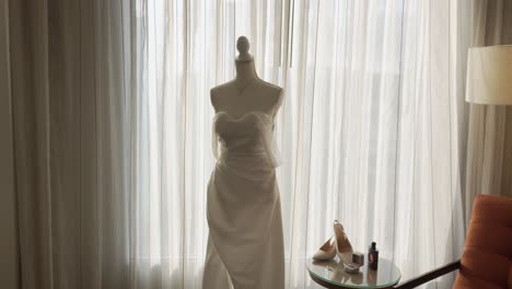 Long-white-dress-on-a-hotel-room-mannequin-during-bride's-preparation