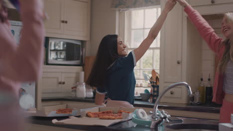 un grupo feliz de adolescentes bailando en la cocina comiendo pizza divirtiéndose celebrando juntos disfrutando de pasar el tiempo juntos en un fin de semana de fiesta