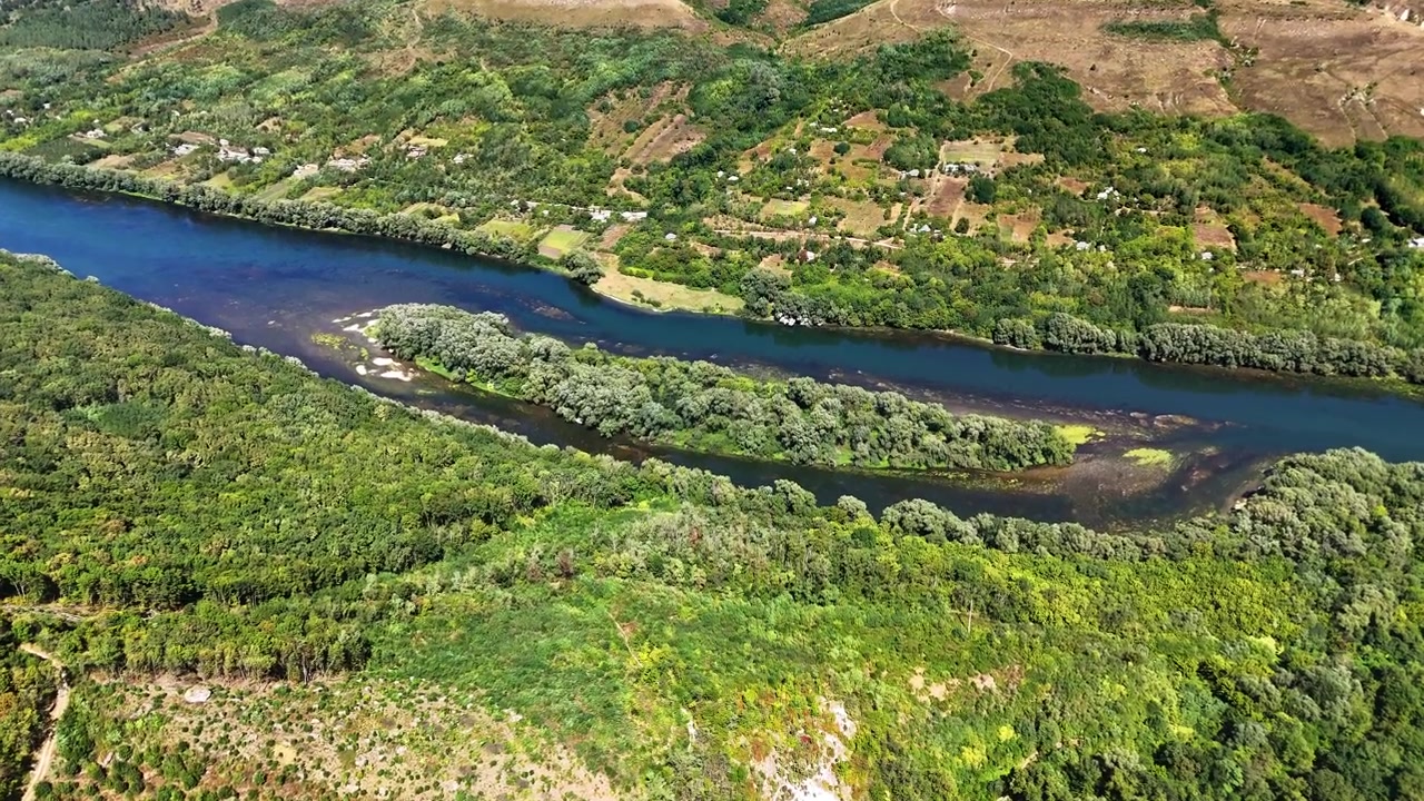 Vista aérea de drone do rio Dniester azul correndo abaixo de encostas verdes e pequenos vinhedos, Rio Dniester, Moldávia