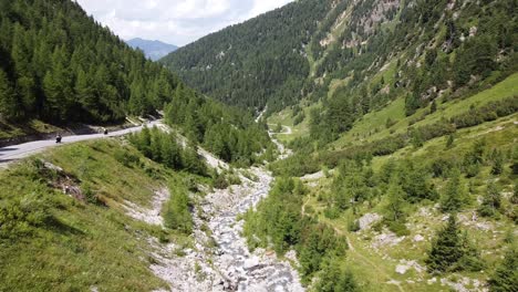 parque nacional suizo - vista aérea de drones de motocicletas que recorren el verde valle y el río de la montaña