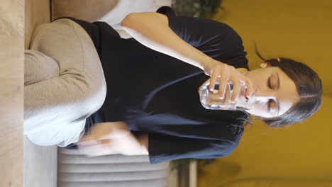 vídeo vertical de una joven cobarde bebiendo agua con la mano temblorosa.