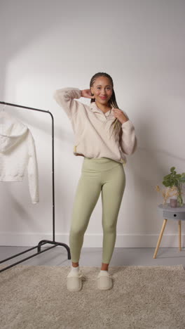 vídeo vertical de pov de una influyente femenina de las redes sociales produciendo contenido generado por el usuario en el estudio modelando una variedad de trajes de moda filmados en tiempo real 9
