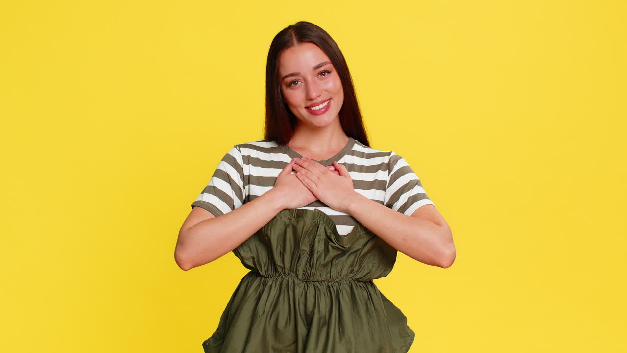 Young woman girl holding hands on chest expressing deep gratitude thankful emotional reaction