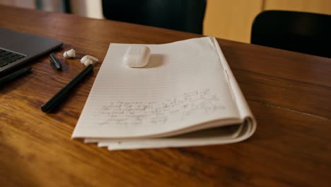 workspace with laptop, notebook, and earbuds