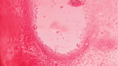 macro shot of bright red water with many sparkling bubbles leaving a little spot without bubbles