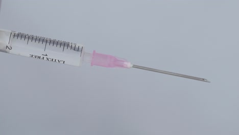 attaching needle to syringe with fluid - coronavirus vaccine concept - close up