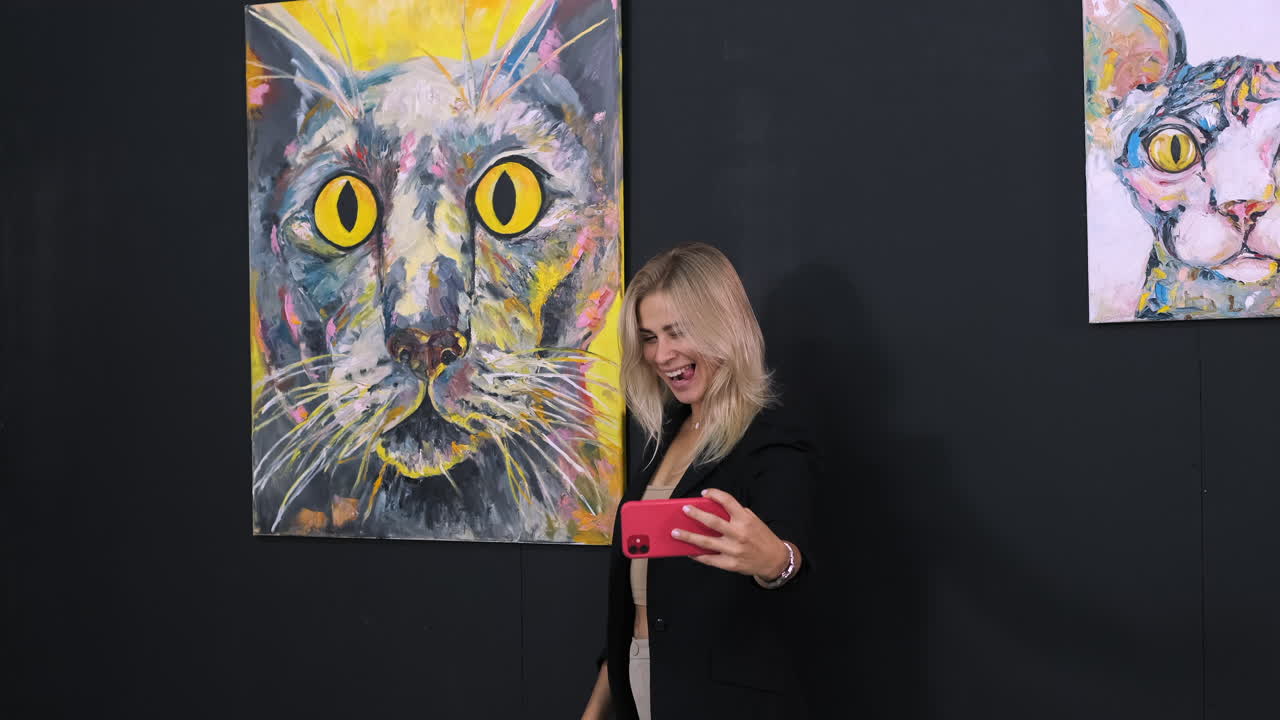 고양이 그림 앞에서 셀피를 찍는 여자