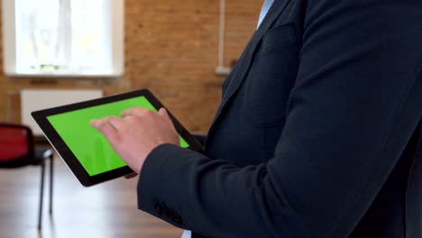 hombre usando una tableta negra con pantalla verde en una oficina moderna. clave de croma. cerca.