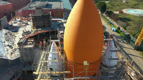 aerial close-up shot tilting in front of a orange space rocket, sunny day in usa