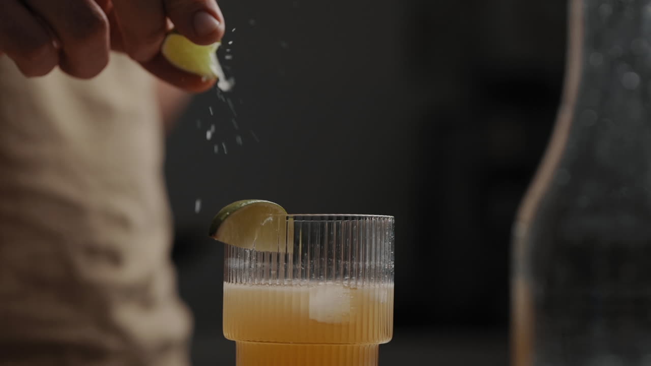 Young Male squeezing lime or lemon over fresh mixed cocktail in a drinking glas  4K Slow Motion Close Up