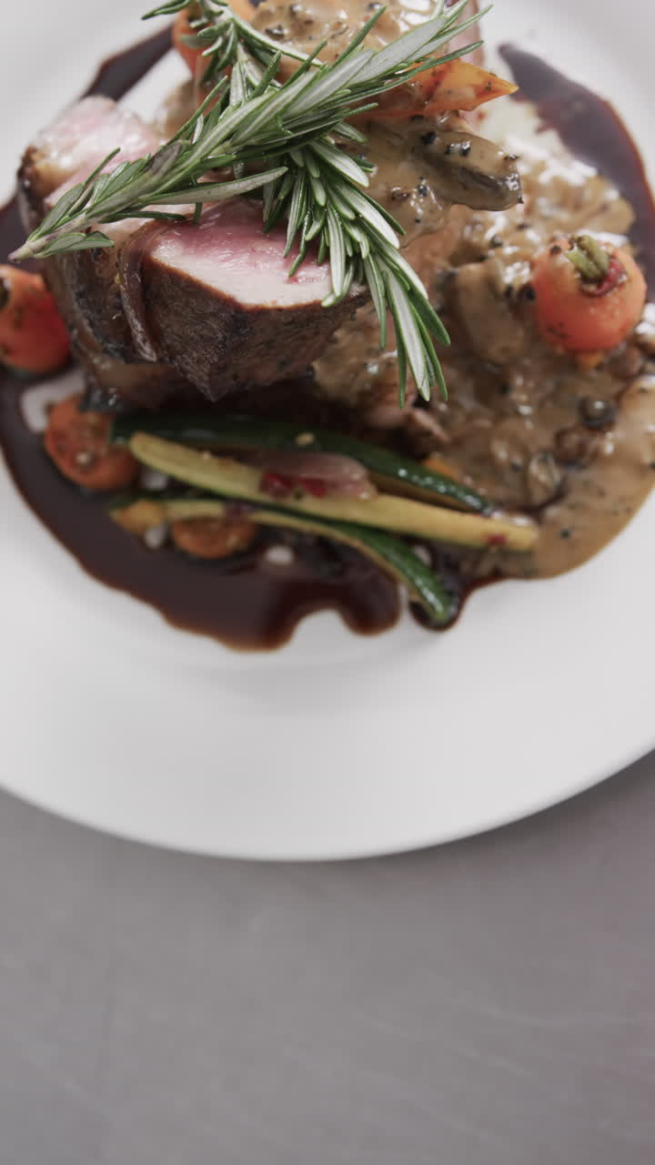 Upper view of prepared and decorated meal on white plate on in kitchen, slow motion, vertical