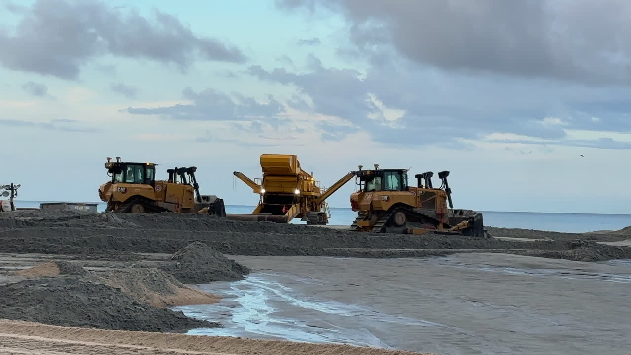Bulldozers leveling sand, beach replenishment sustainability project