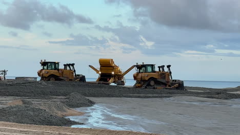 bulldozers leveling sand, beach replenishment sustainability project