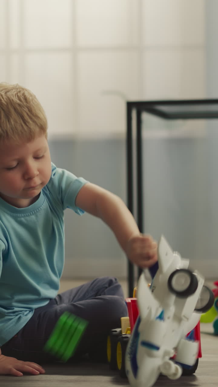Little boy plays with airplane while sister building house from colorful plastic constructor blocks. Toddler enjoys transport toys at home closeup
