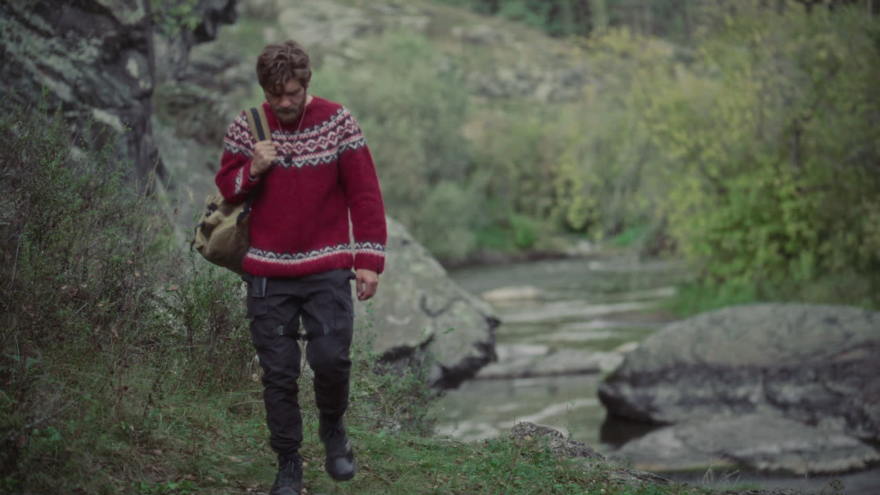 Man with Backpack Hiking along Rocky Forest Riverbank