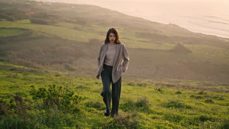 attractive girl climbing hill covered green grass. woman walking near calm ocean