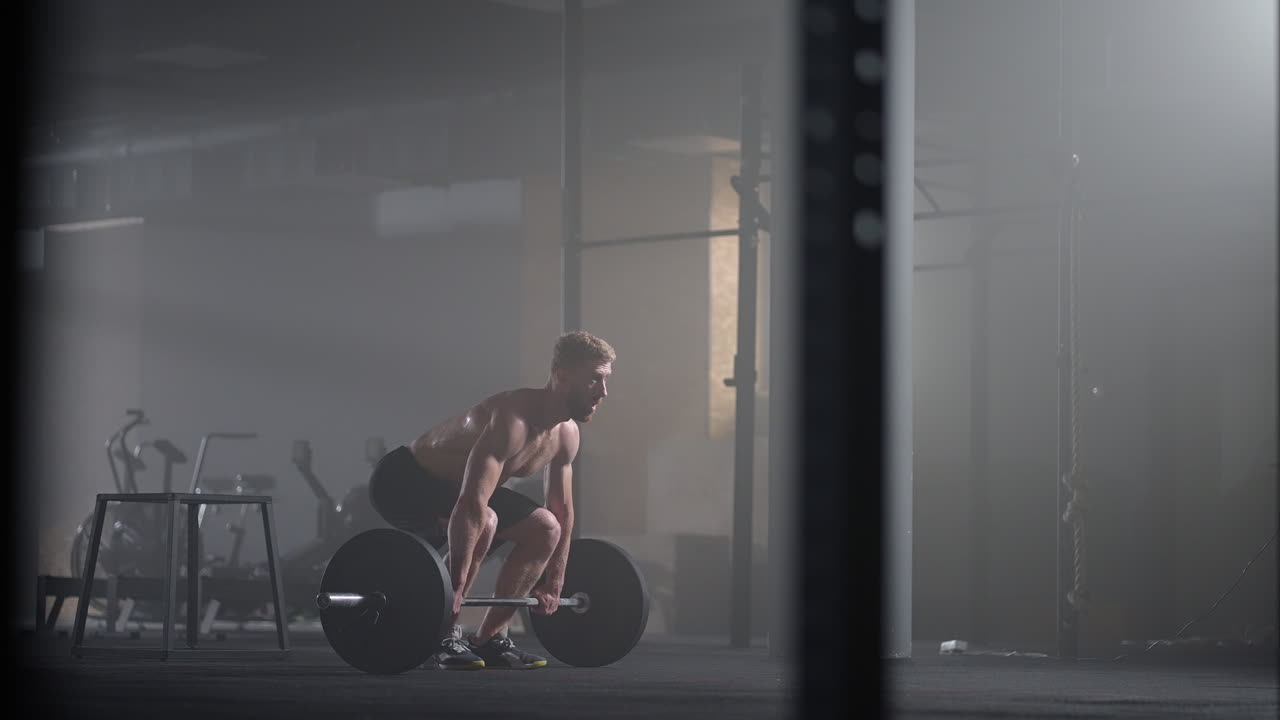 Slow motion of crossfit athlete performs clean and jerk. Young man doing the clean and jerk weightlifting exercise at the gym.