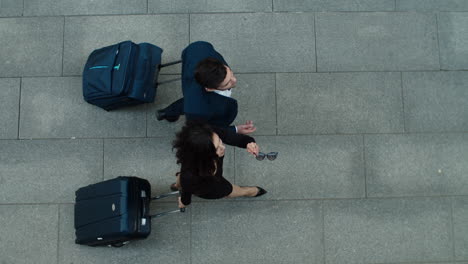 Top-view-couple-walking-with-luggage.-Business-partners-talking-together