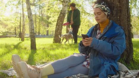woman sitting in park and using smartphone
