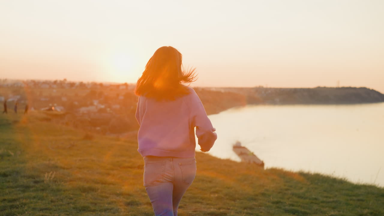 mujer corre a lo largo de la orilla vacía del río al atardecer luz mujer deportiva en vaqueros corre en la orilla del río del país