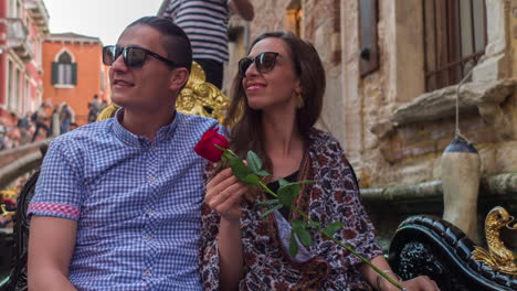 couple enjoying a gondola ride in venice with a red rose