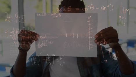 ecuaciones matemáticas flotando contra un niño afroamericano con un papel en la escuela primaria