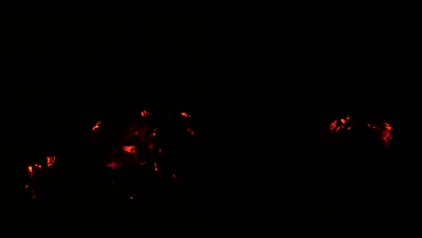 las brasas moribundas de un fuego en la oscuridad. leña ardiente. llama de fuego. horno rural. chimenea ardiente. fogata turística por la noche. combustión de madera. emergencia. riesgo de ignición. humo.