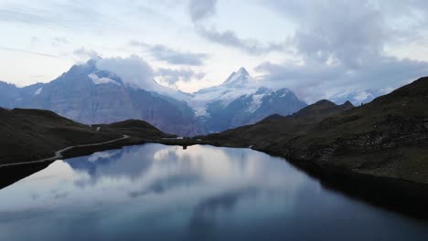 Sobrevuelo-Aéreo-Sobre-El-Lago-Bachalpsee-En-Grindelwald,-Suiza-Al-Atardecer-Con-Un-Reflejo-De-Los-Picos-Schreckhorn-Y-Wetterhorn