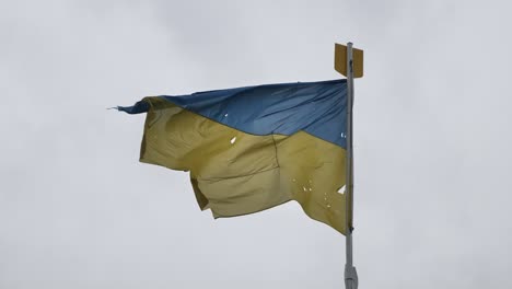 Bandera-Ucraniana-Dañada-Ondeando-Durante-La-Guerra-En-Ucrania,-Bandera-Oficial-Nacional-Ucraniana-Ondeando-Durante-Tiempos-De-Guerra