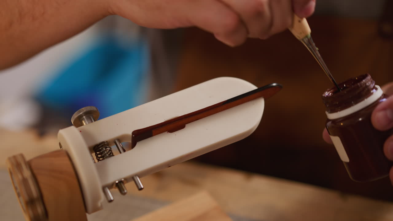 남자가 가죽 세부 사항에 갈색 페인트를 적용하고 클램프로 고정합니다.