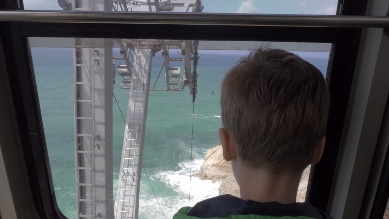 Junge blickt aus fahrender Seilbahn in Rosh Hanikra aufs Meer