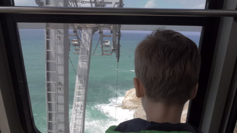 niño mirando al mar desde el funicular en movimiento en rosh hanikra