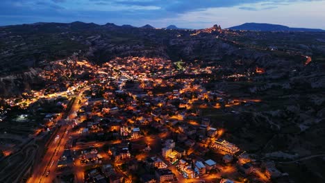 aerial view of a lit town at dusk with mountains in the background