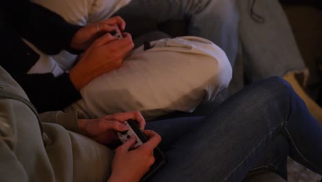 two people sitting closely together, each engaged in manipulating small, handheld devices game controllers