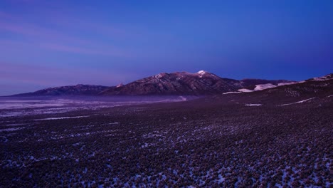 the end of a sunset on the side of a large snowy mountain peak