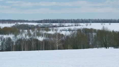 early spring snowy landscape with flying clouds on sky. snowy field covered with white snow. pan.
