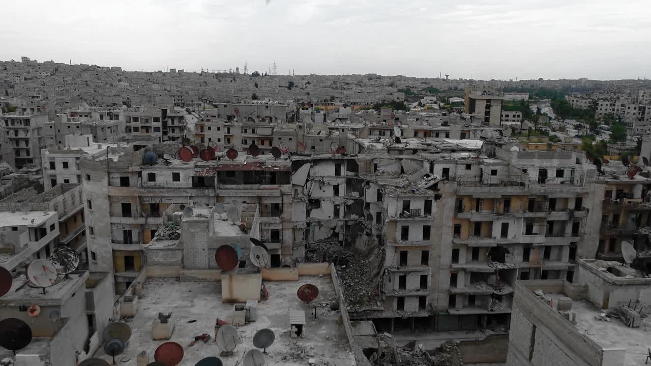 Aerial view above roofs of buildings in Aleppo, Syria. There is antenna rusted with time on the rooftop, the city is in ruins 4K