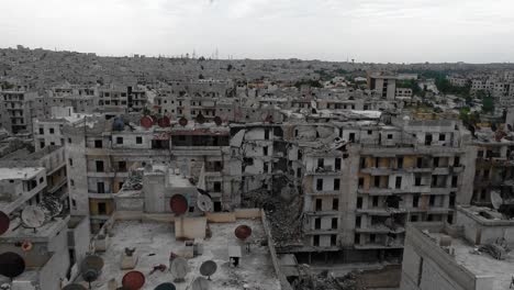 aerial view above roofs of buildings in aleppo, syria. there is antenna rusted with time on the rooftop, the city is in ruins 4k