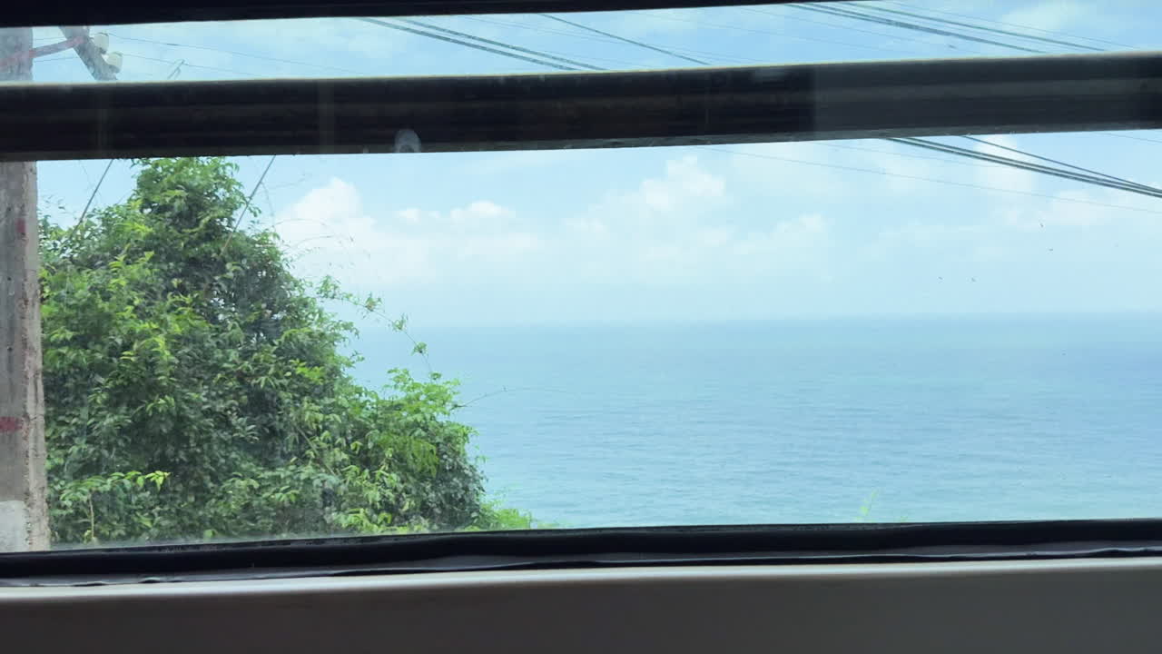 Vista através da janela de um trem em movimento passando por densa vegetação verde no Vietnã central, capturando o cotidiano das viagens de trem, o movimento borrado do campo e uma paisagem tropical tranquila.