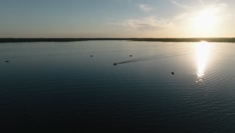 aerial drone shot of boats on a large lake with the sun setting in the background