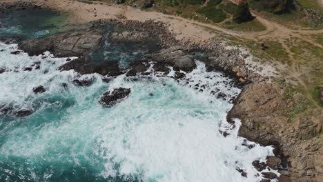 captivating aerial shot of waves crashing against the rocky shoreline at playa chica, quintay, valparaíso, showcasing the natural beauty and rugged coastline of chile