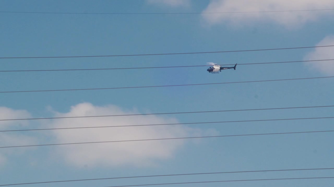 LAPD-polishelikopter flyger mot blå himmel i Los Angeles, vidvinkelbild dagtid.