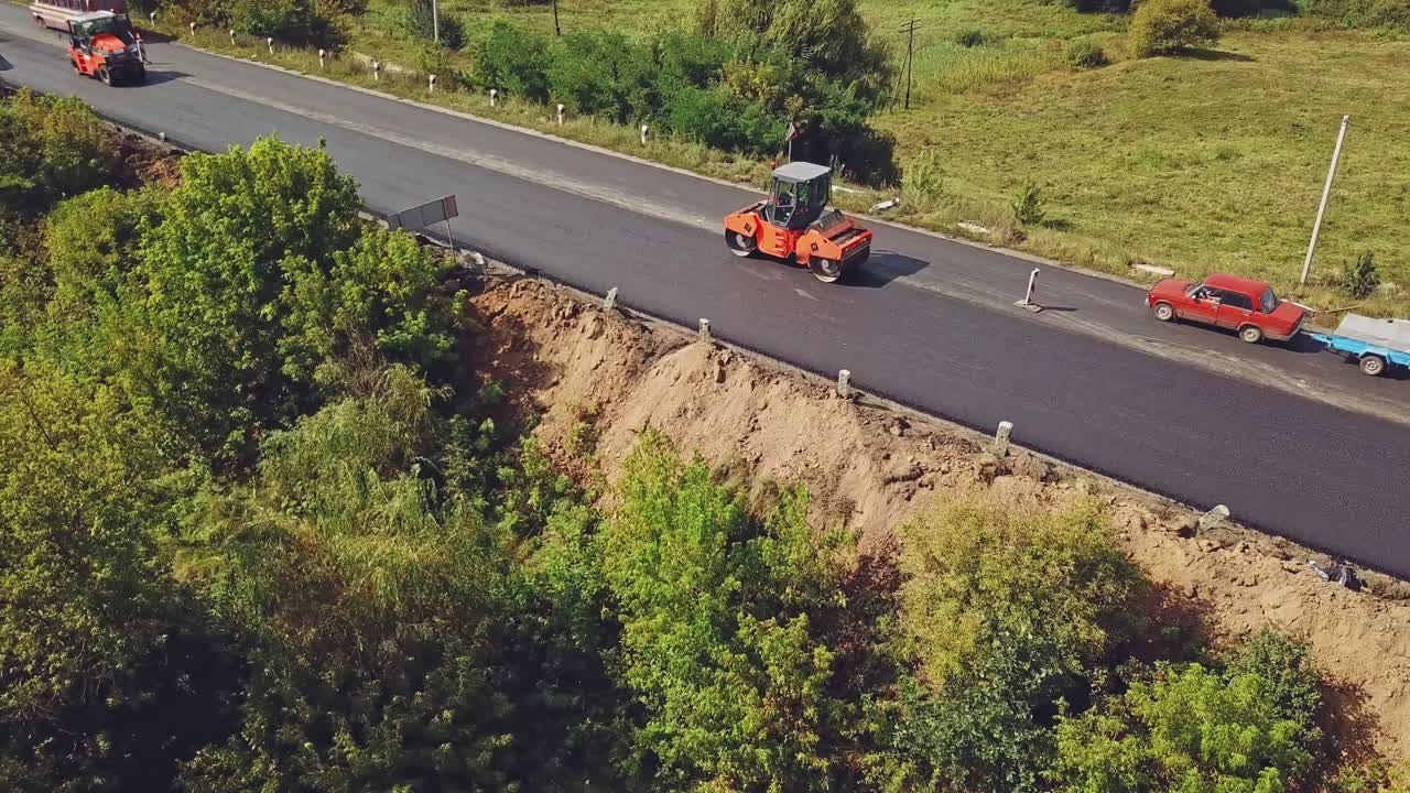 Aerial view. Laying a new asphalt on the road. Road repair machine with heavy vibration roller compactor