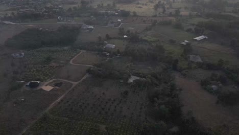 Reveal-drone-shot-on-the-morning-foggy-mountains-during-the-sunrise-with-village-underneath