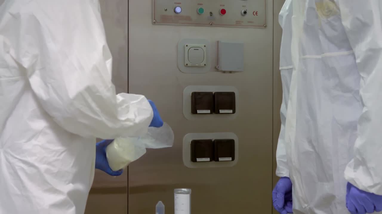 ученые в защитных костюмах работают вместе.