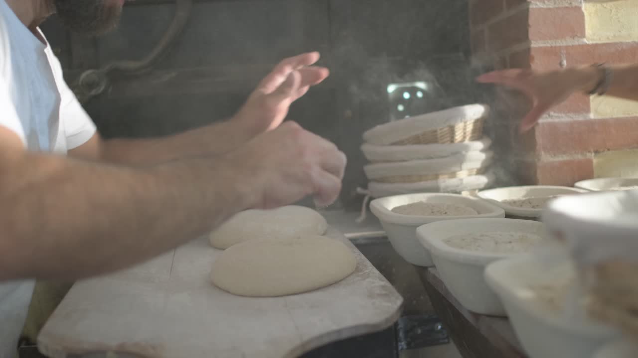 Close-up de um padeiro enfarinhando, cortando e colocando pão em um forno de pedra tradicional, usando uma pá de padeiro